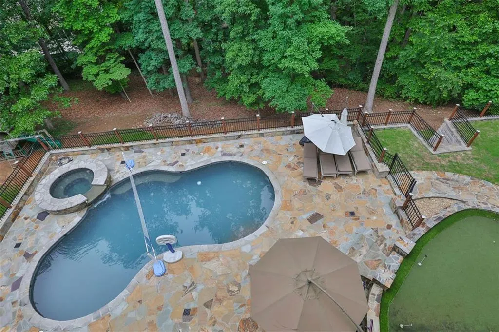View of swimming pool featuring a patio area and an in ground hot tub, Putting green in view