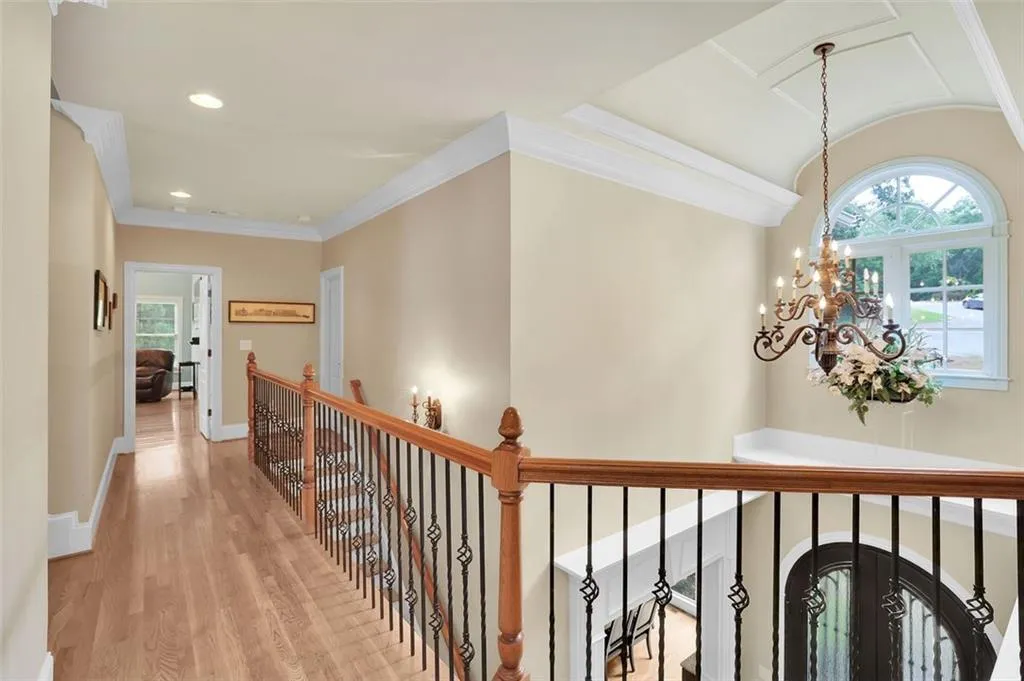 Hall featuring light hardwood / wood-style flooring, ornamental molding, an inviting chandelier, and french doors
