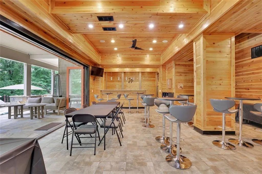 Open recreation room (sub basement level) with wall to wall accordion doors that fold to open up the space to the outdoors. Also has retractable screen featuring wood ceiling, ceiling fan, and light tile floors