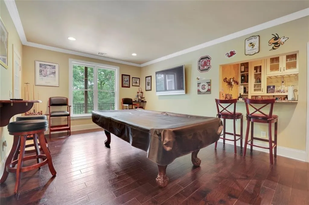 Game/flex room with bar featuring dark hardwood / wood-style flooring, billiards, and ornamental molding