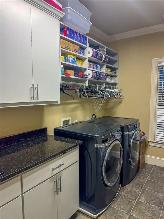 Laundry area with separate washer and dryer, crown molding, cabinets, hookup for a washing machine, and dark tile flooring