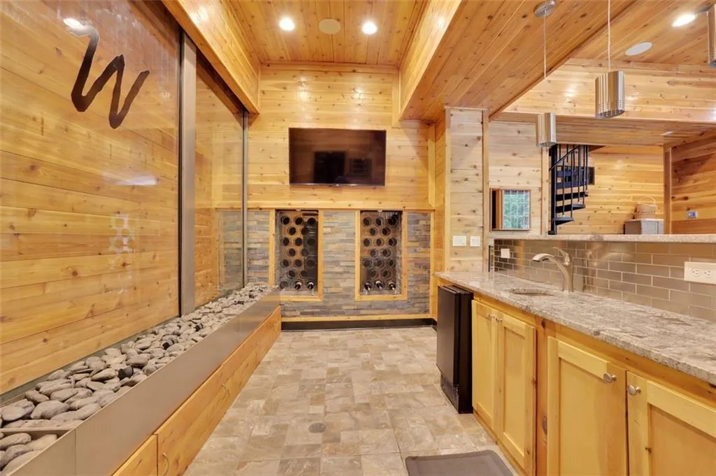 Bar (sub basement level)  with wine storage, wood ceiling, sink, decorative light fixtures, and light tile floors