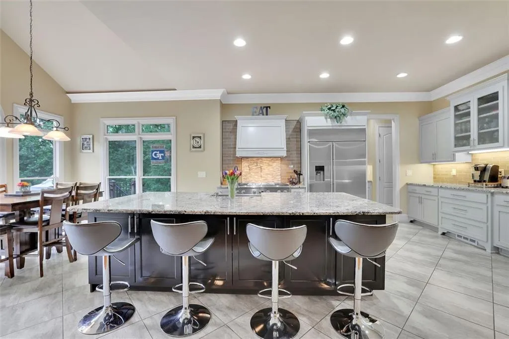 Kitchen with a breakfast bar area, a kitchen island with sink, built in fridge, and backsplash
