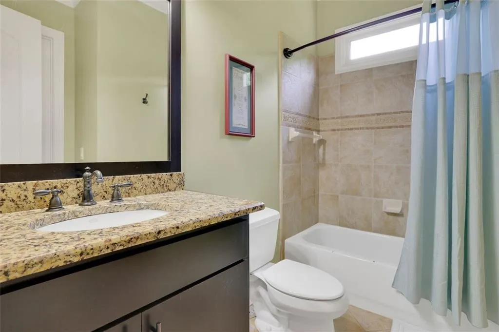 Full bathroom featuring shower / bath combination with curtain, vanity, toilet, and tile floors