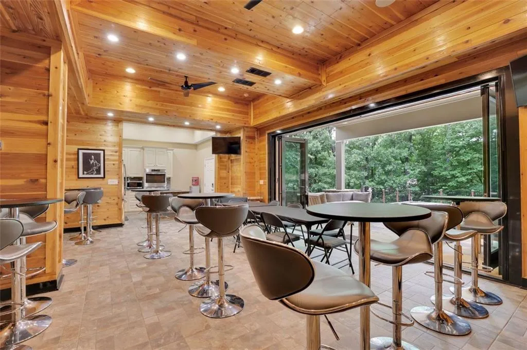 Open recreation room (sub basement level)  featuring wood ceiling, ceiling fan, and light tile floors ceiling fan, a tray ceiling, wooden ceiling, and light tile floors