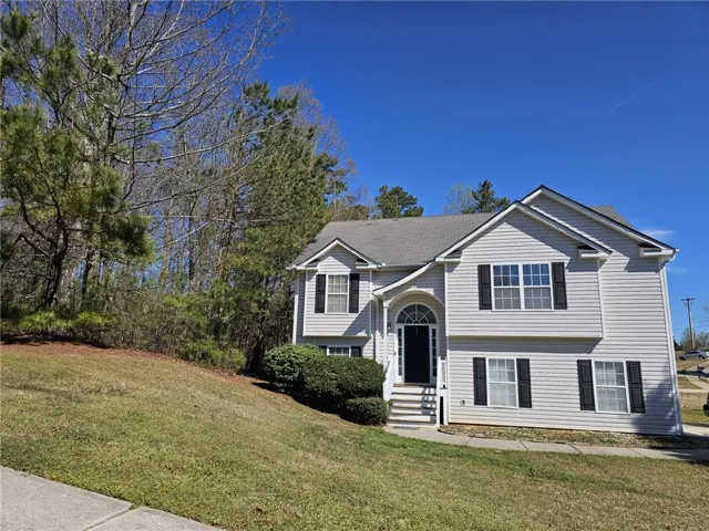 Two-story colonial-style home featuring white vinyl siding, black shutters, and a covered front entrance with pillared support