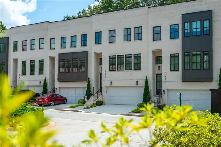 Contemporary multi-level townhome featuring a light brick facade and dark-framed windows