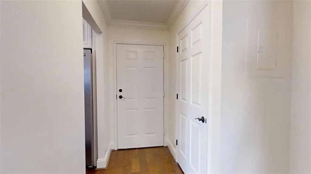 Hallway featuring dark wood-type flooring, electric panel, and ornamental molding