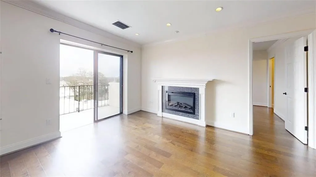 Unfurnished living room with ornamental molding, a glass covered fireplace, wood finished floors, and recessed lighting