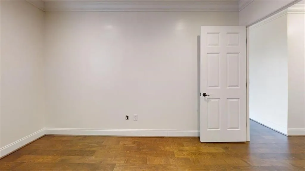 Empty room featuring crown molding and dark wood-type flooring