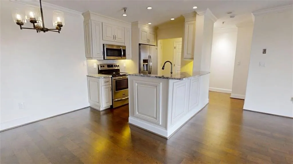 Kitchen featuring stainless steel appliances, light stone countertops, tasteful backsplash, ornamental molding, and dark wood-type flooring