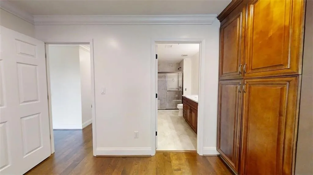 Hallway with dark wood finished floors and ornamental molding