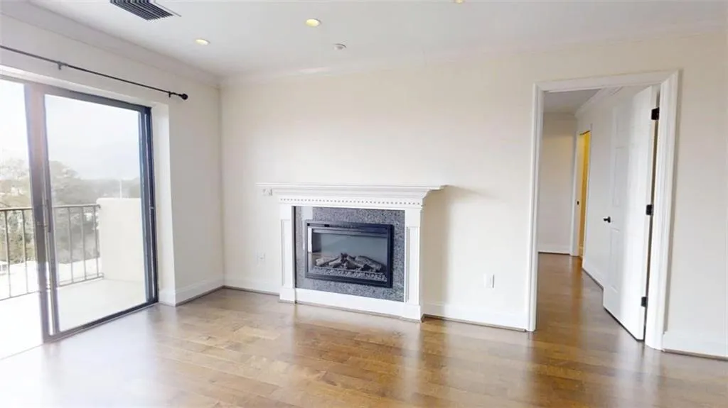 Unfurnished living room featuring wood finished floors, crown molding, a glass covered fireplace, and recessed lighting