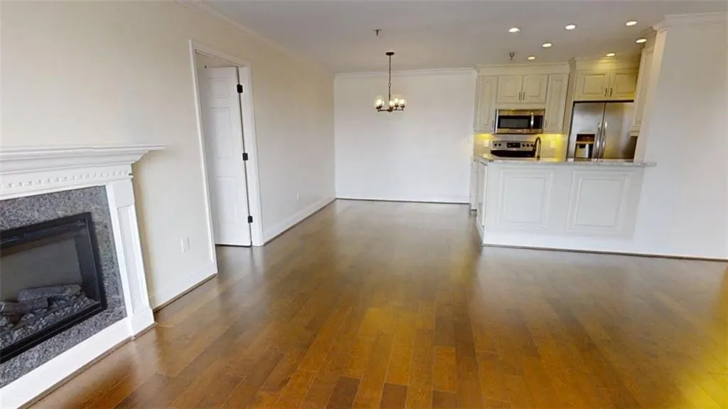 Kitchen featuring appliances with stainless steel finishes, a chandelier, ornamental molding, open floor plan, and a glass covered fireplace