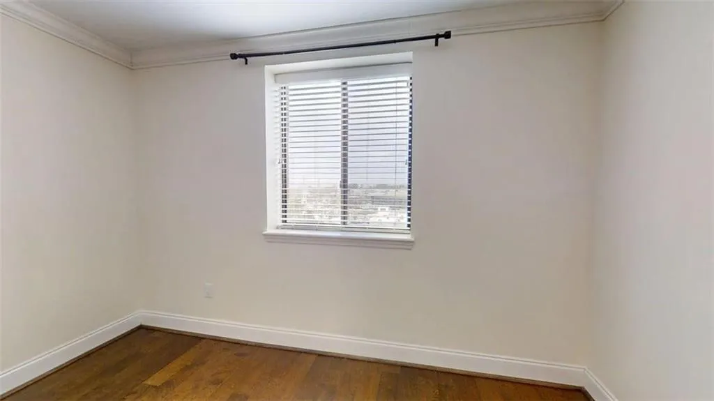 Spare room featuring crown molding and dark wood-type flooring
