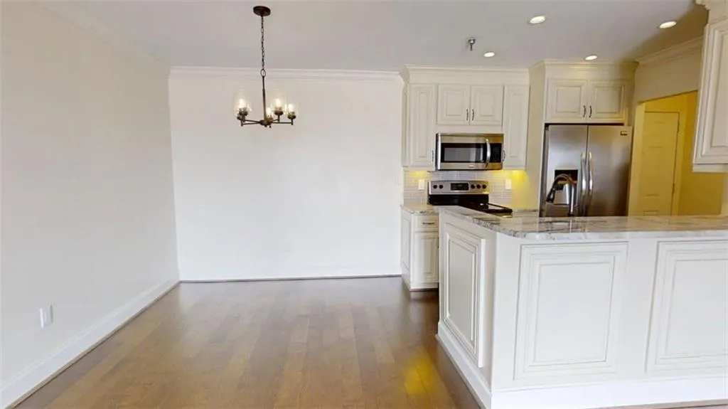 Kitchen featuring appliances with stainless steel finishes, light stone counters, backsplash, crown molding, and decorative light fixtures