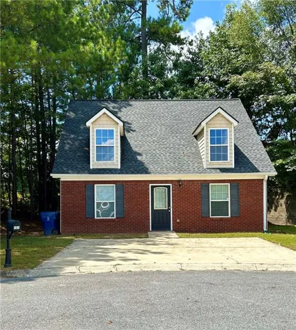 Brick exterior with a dark shingle roof, featuring two dormer windows with siding accents