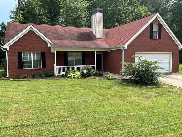 Brick exterior with a covered porch, white balustrade, and a two-car garage