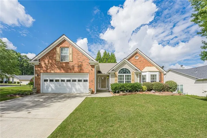 Brick facade with a gabled roofline, arched window, bay window, and an attached two-car garage