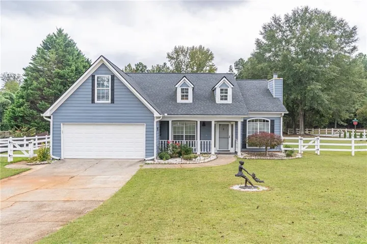 Two-story residence featuring blue siding with white trim, a dark shingle roof, and a two-car garage
