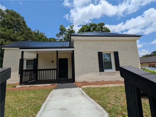 Light-colored brick exterior featuring a black metal roof