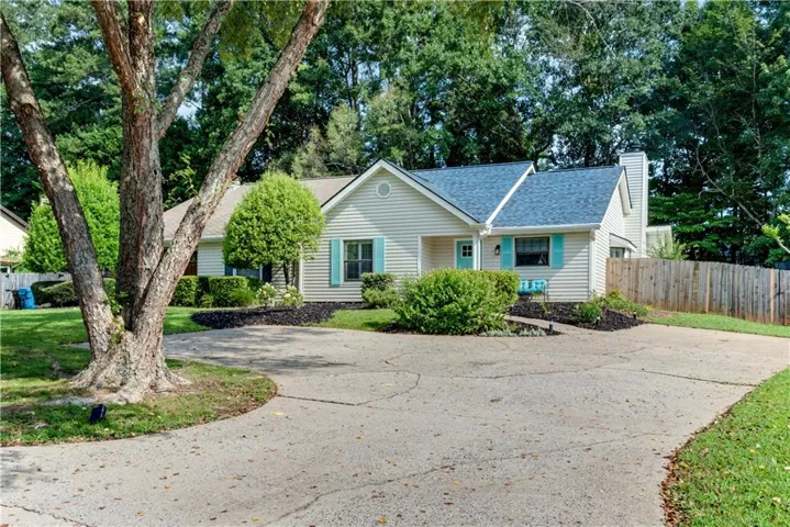 Siding exterior with a gabled roof, light blue shutters, and a wooden privacy fence