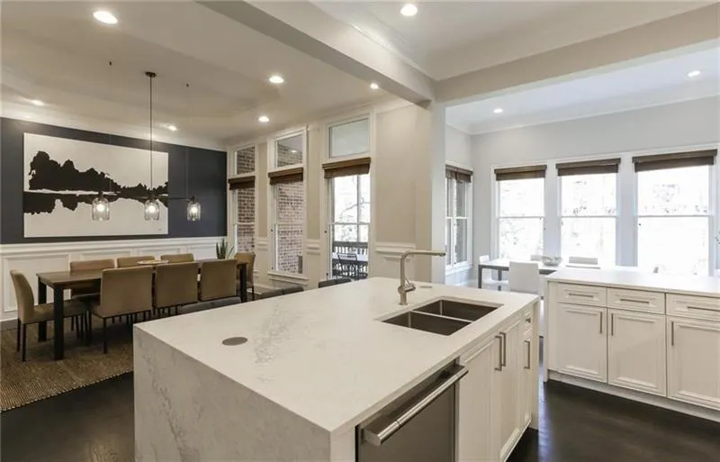 Whether you are downsizing or upsizing - there is so much room in this attached property that you will never feel cramped. Here you have a view from the kitchen showing the dining room, oversized kitchen island, eat in kitchen dining space as well as the main level covered deck overlooking the wooded backyard! This is truly ideal function and flow for a group of any size!