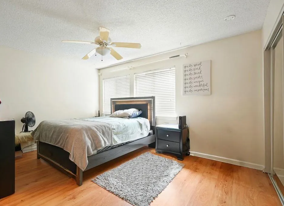 Bedroom with a textured ceiling, light wood finished floors, and ceiling fan