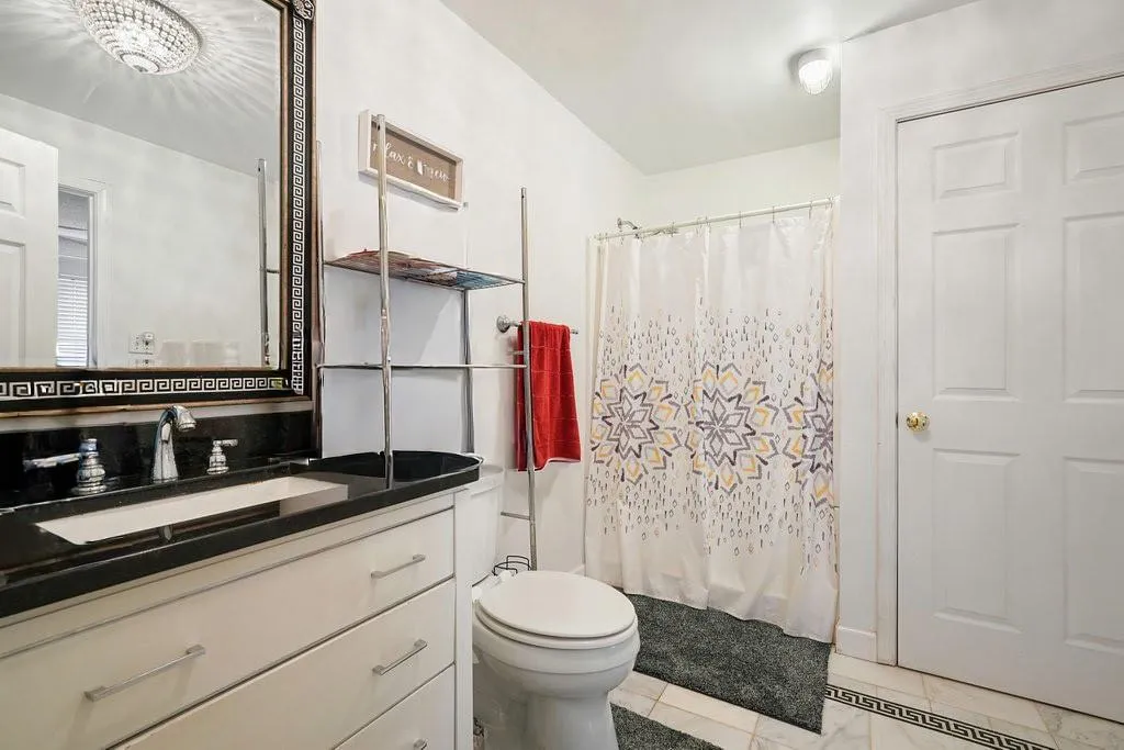 Bathroom featuring vanity, light tile patterned flooring, and curtained shower