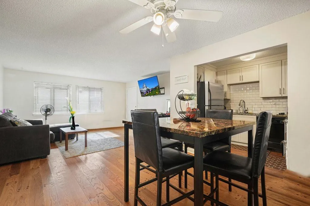 Dining area with a textured ceiling, light wood-style floors, and a ceiling fan