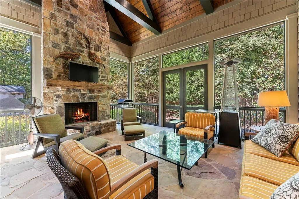 Outdoor living space with screened porch and stacked stone fireplace calls for both cozy cool days and warm summer nights.