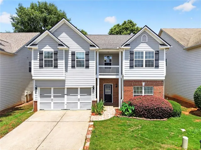 Two-story residence featuring light gray siding, brick accents, and a two-car garage