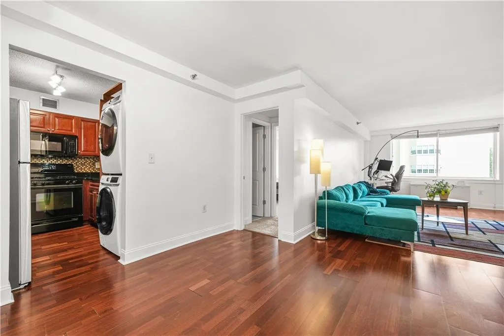 Living area with dark wood finished floors and stacked washing machine and dryer