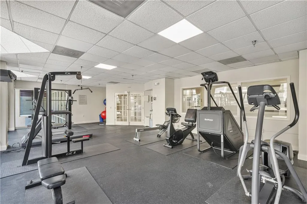 Workout area with a drop ceiling and baseboards
