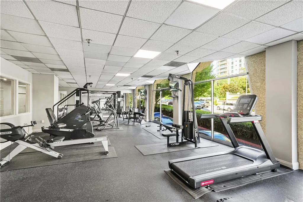 Workout area featuring a drop ceiling and a wall of windows