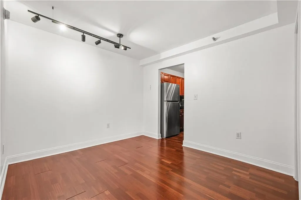 Unfurnished room with dark wood-style flooring and rail lighting