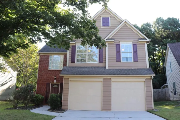 Two-story exterior with a brick and siding facade, featuring a two-car garage, multiple gables, and decorative window shutters