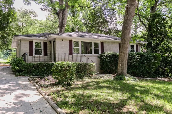 Ranch-style exterior with light-colored brick siding, dark shutters, and a dark asphalt shingle roof