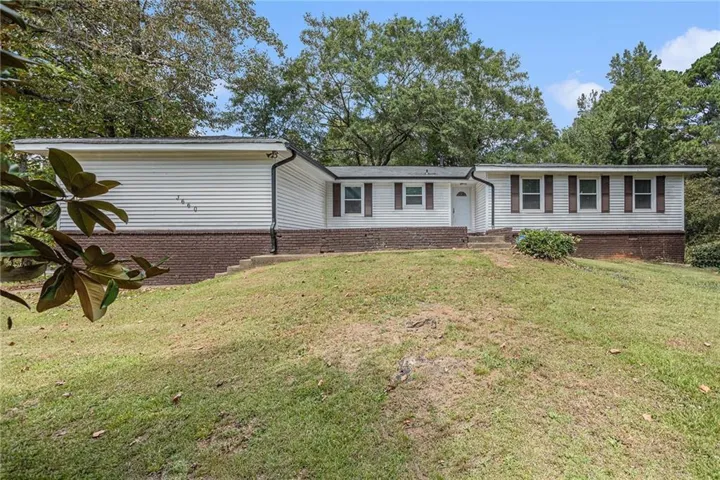 Exterior featuring white siding, a brick foundation, and brown window shutters
