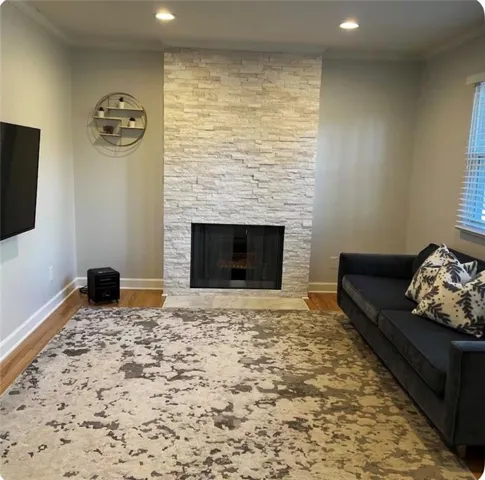 Stacked stone fireplace with a black glass enclosure, recessed lighting, and wood-finish flooring