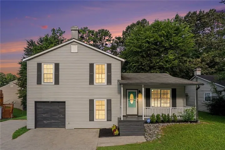 Two-story property featuring light gray siding, dark gray shutters, and a covered front porch with white railings