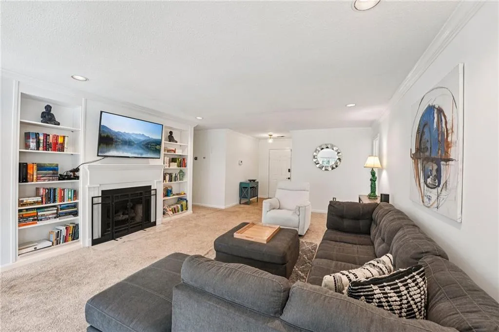 Living room featuring built in features, a fireplace, carpet flooring, ornamental molding, and recessed lighting