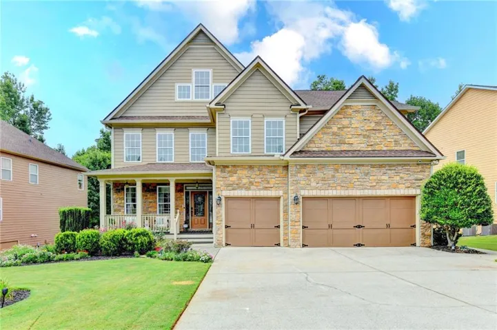 Elegant two-story colonial featuring a stone and siding exterior with multiple gables and peaked rooflines