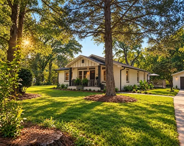 White brick exterior with dark trim accents, covered front porch, expansive lawn, mature trees, and detached garage