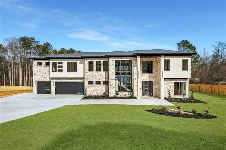 Modern home featuring an attached garage, driveway, brick siding, and stucco siding