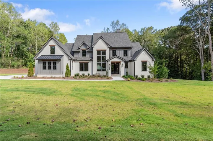 Two-story residence featuring a mixed-material facade, gabled rooflines, dark-framed windows, and a wide front lawn