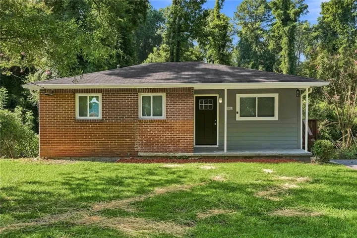 Single-story residence featuring a partial brick exterior with grey siding, a dark asphalt shingle roof, and white-framed windows