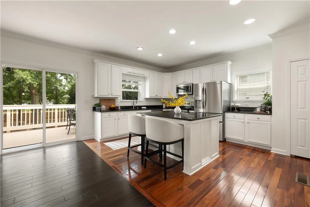 Kitchen with crown molding, recessed lighting, appliances with stainless steel finishes, dark countertops, and white cabinetry