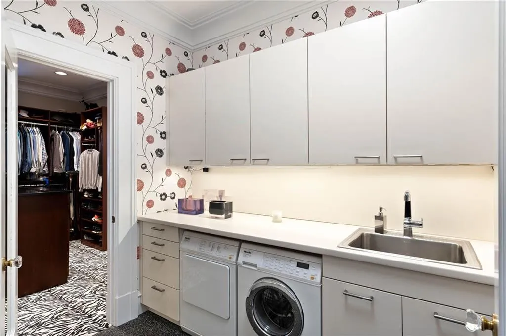 Laundry area featuring crown molding, wallpapered walls, cabinet space, and independent washer and dryer