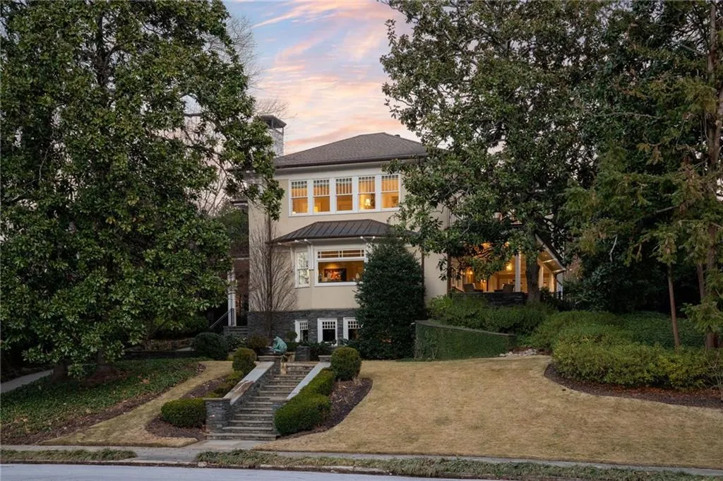View of front of home with a standing seam roof, a lawn, a metal roof, stucco siding, and stairway